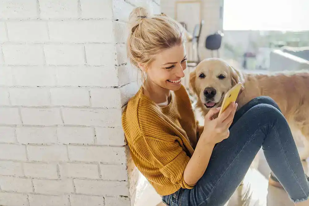 A blonde woman cuddling her Golden Retriever